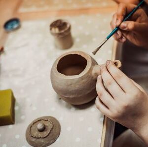 Someone painting a piece of pottery.