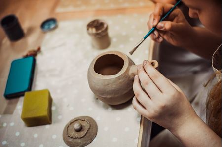 Someone painting a piece of pottery.