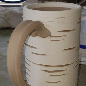 A tan and brown clay coffee mug.